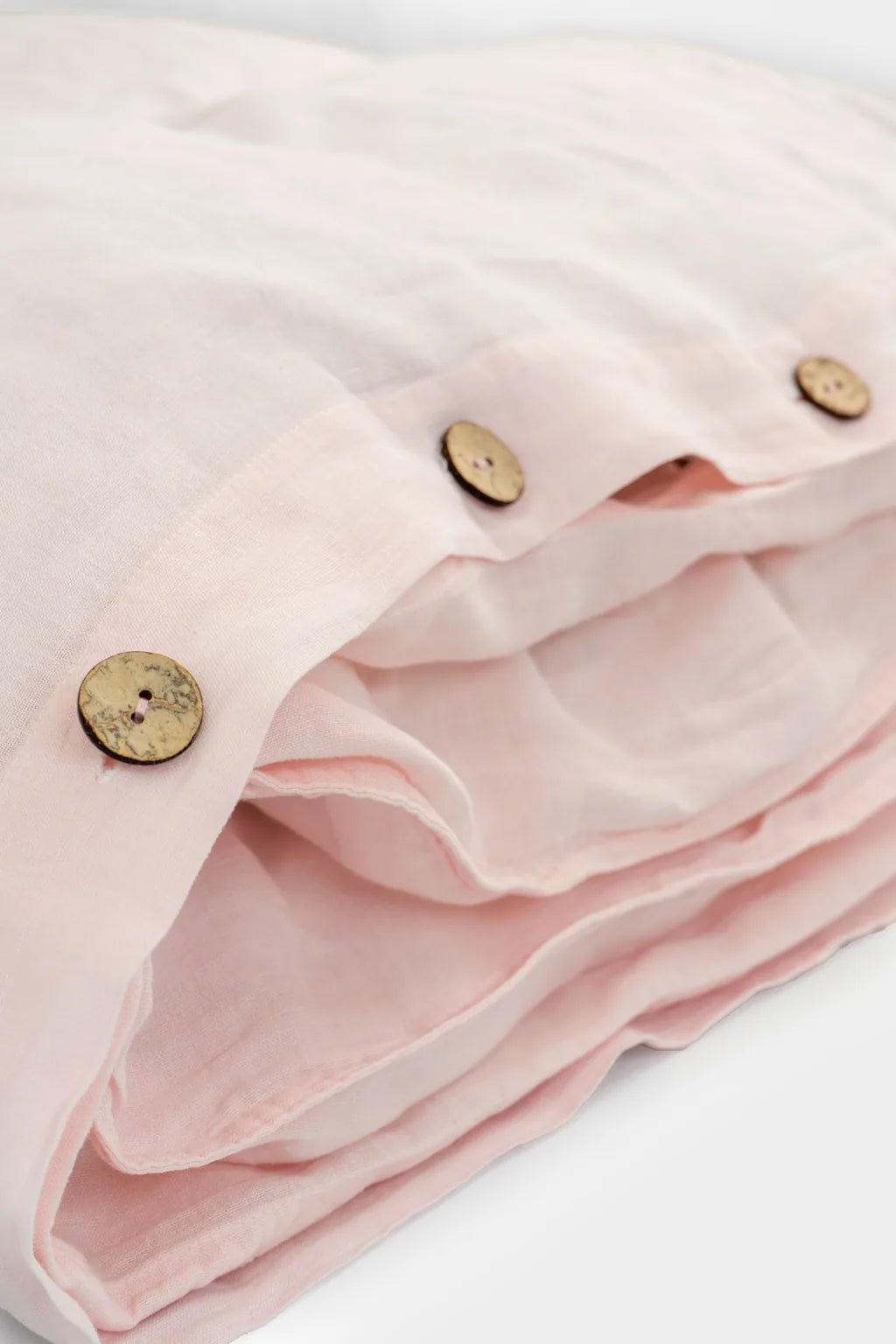 Close-up of rosewater pink Vesta linen bedding with natural buttons