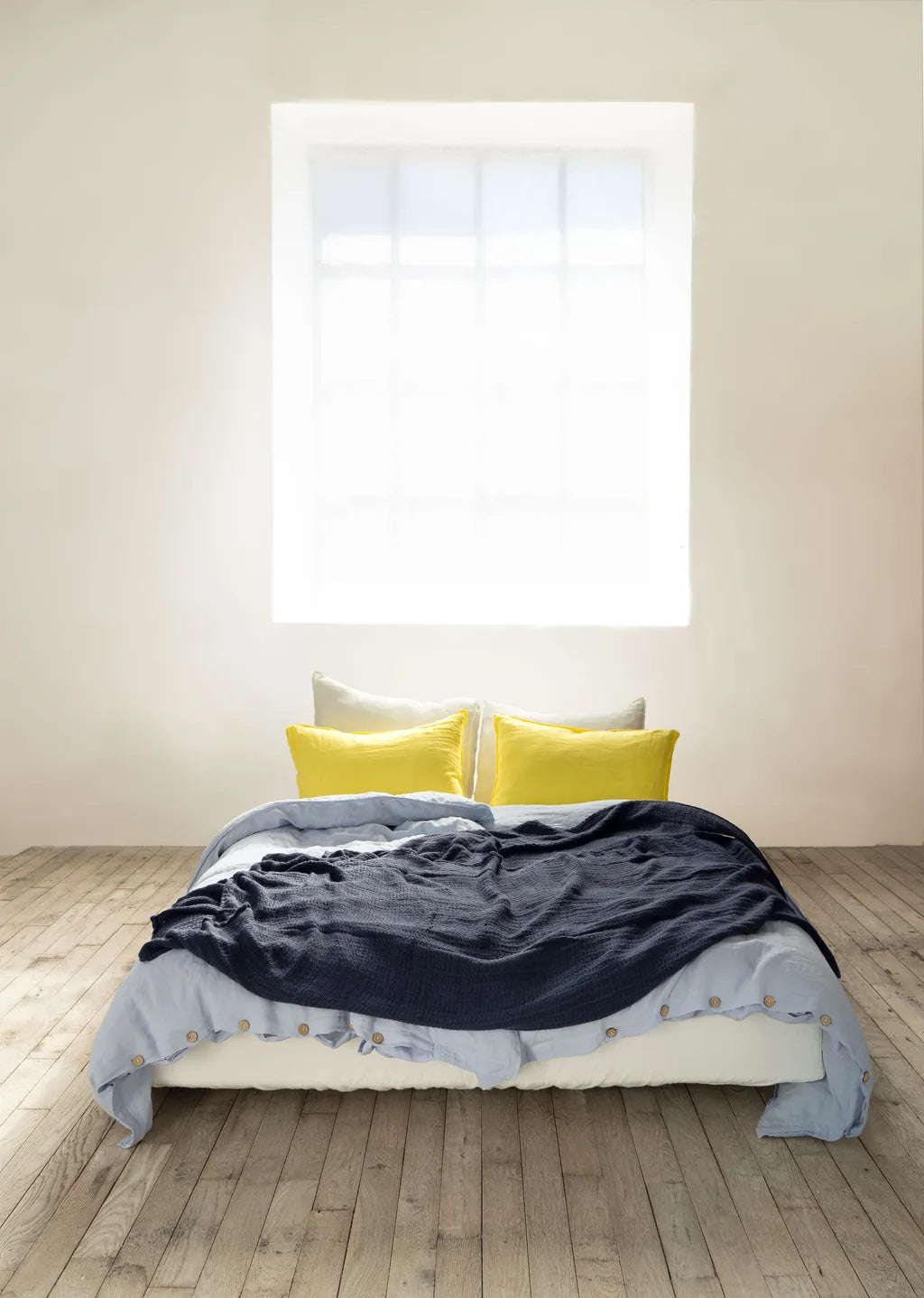 Vesta linen bedding with yellow pillows and a deep navy throw